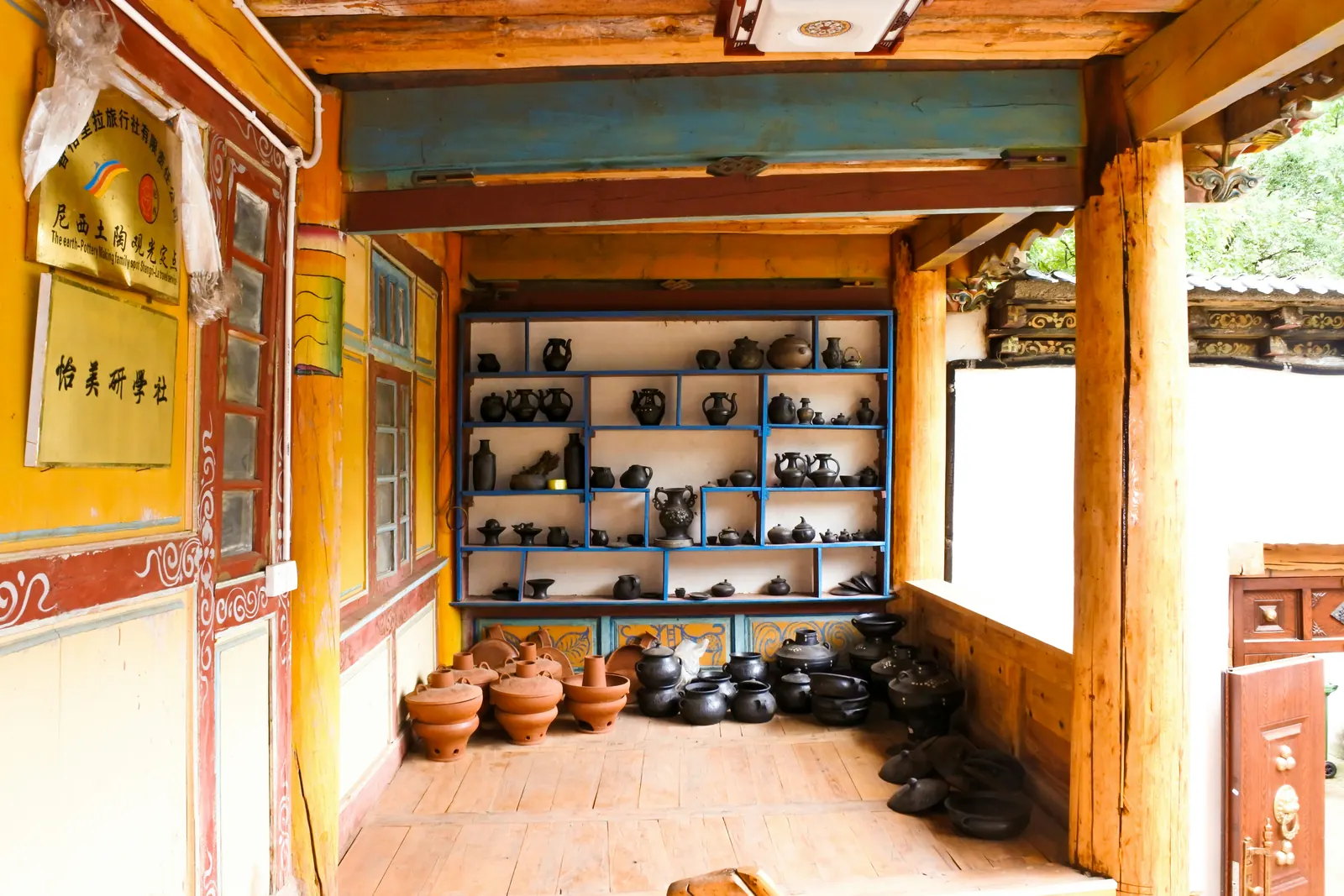Dark pottery and terracotta vessels displayed in a sunlit wooden interior